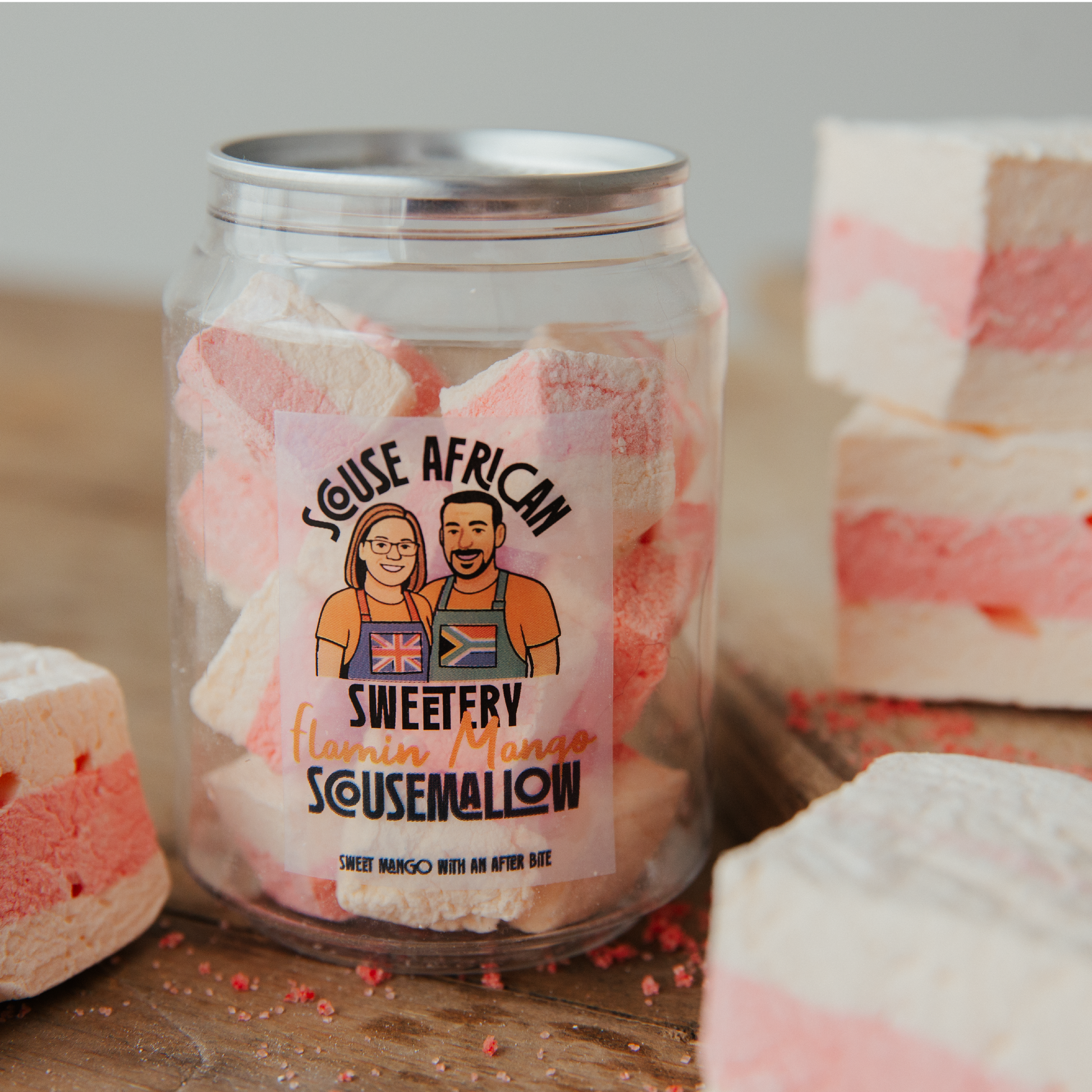 Jar of red and orange marshmallows with a label on a wooden surface