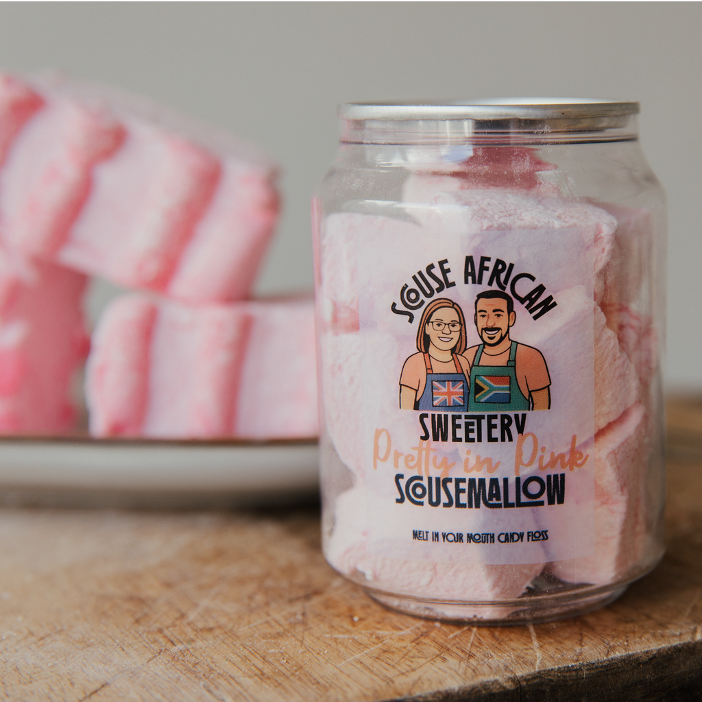 Can of pink marshmallows with a label featuring two people and text on a wooden surface.