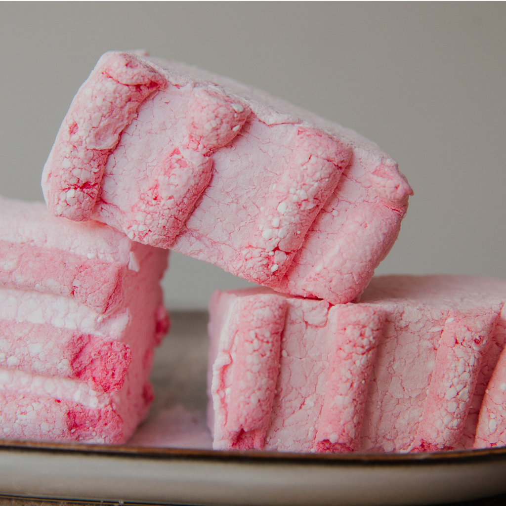 Pink textured marshmallows stacked on a neutral background