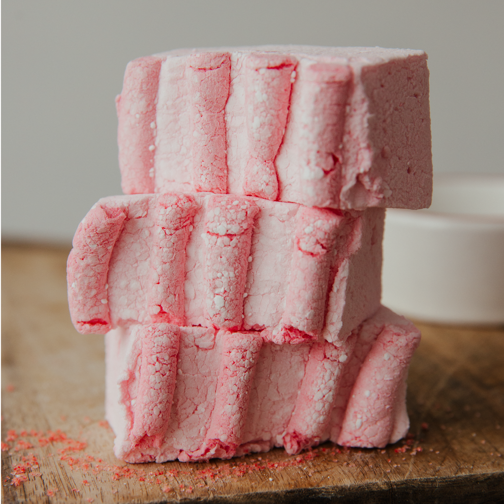 Stack of pink marshmallow on a wooden surface with a blurred background