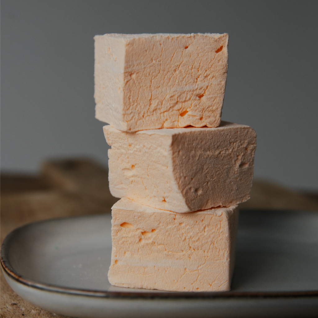 Stack of three marshmallows on a plate with a dark background